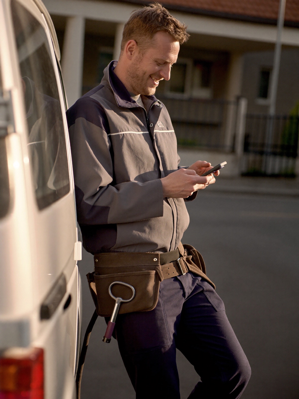 Elektrikář u své dodávky čte SMS od nového zákazníka